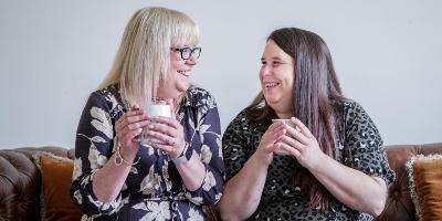 An adult with additional needs drinking a cup of tea with carer as part of Shared Lives scheme