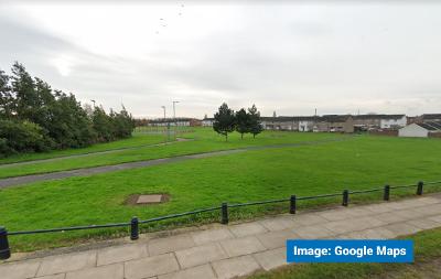 A Google Street View image looking across green space off High Newham Road in Hardwick. The existing multi-use games area can just about be made out.