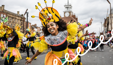 Girl dressed in a bright bumblebee outfit dances at SIRF Carnival in front of Stockton Town Hall